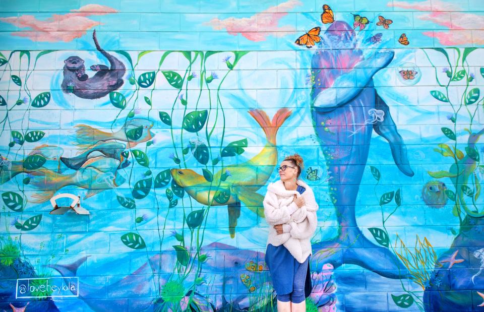 Artist Jessica McGhee stands by her new mural, "Vivarium," on the back patio of One World Cafe, 1245 W. Main St. in Peoria. McGhee painted over an old mural that was decaying and damaged by recent renovations to the popular restaurant. The new mural is also part of a renewed effort to reinvigorate and expand the art scene at One World.