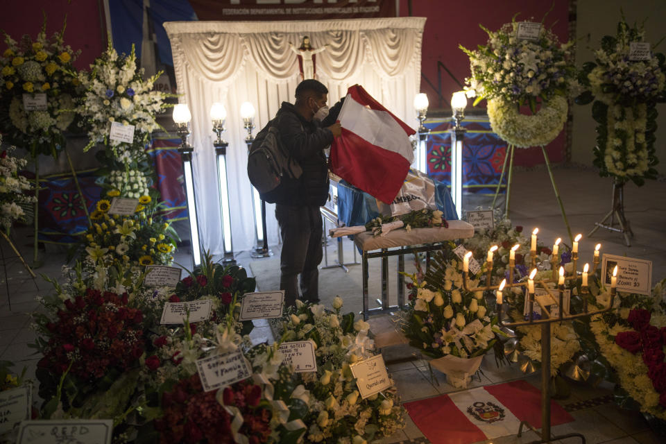 A man puts a Peruvian flag on top of the coffin of Inti Sotelo Camargo, 24, a student who was killed by the police during anti-government protests a day earlier, during his burial in Lima, Peru, Sunday, Nov. 15, 2020. Interim President Manuel Merino announced his resignation following massive protests unleashed when lawmakers ousted President Martin Vizcarra. (AP Photo/Rodrigo Abd)