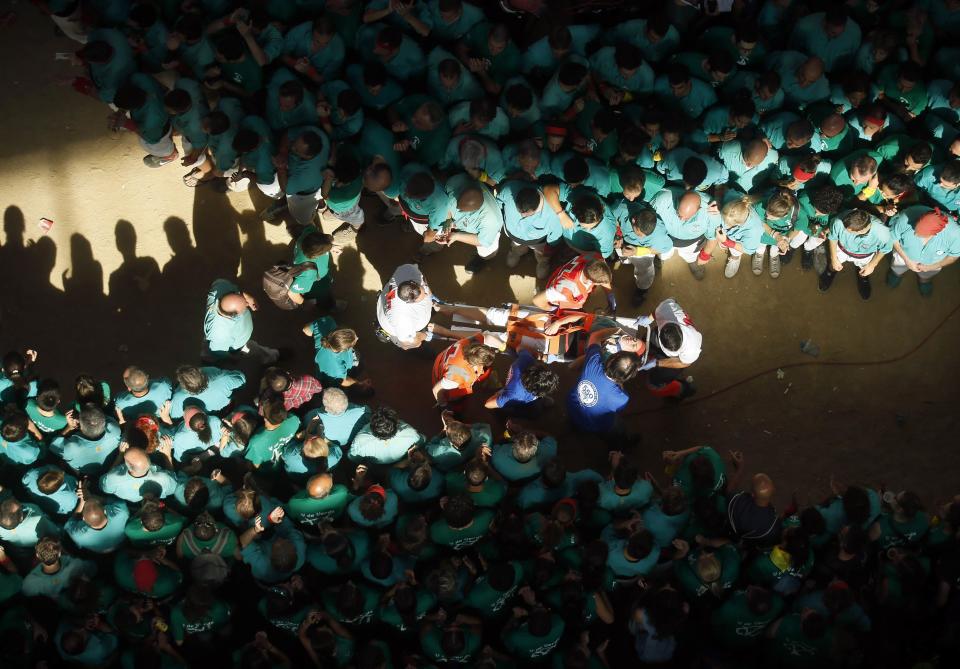 Medical staff carry a member of Castellers de Vilafranca who fell while forming a human tower, called "castell", during a biannual competition in Tarragona city October 5, 2014. The formation of human towers is a tradition in the area of Catalonia. (REUTERS/Albert Gea)