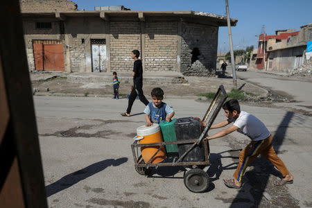Children collect water in containers on a street in eastern Mosul, Iraq, April 19, 2017. REUTERS/Marko Djurica