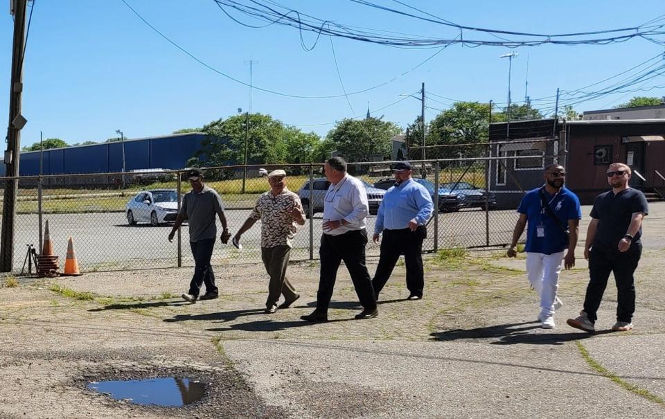Community members taking a walking tour of important offshore wind development sites along the New Bedford waterfront join Foss Marine Terminal President Andrew Saunders, center, as they walk around to the back side of the property towards the water.