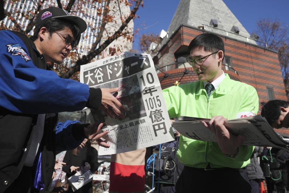 A staff distributes an extra edition of the Yomiuri Shimbun newspaper reporting on Shohei Ohtani to move to the Los Angeles Dodgers Sunday, Dec. 10, 2023, in Tokyo. (AP Photo/Eugene Hoshiko)