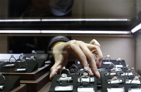A sales assistant reaches for diamond rings inside a display case at a Tiffany store in Shanghai, September 16, 2013. REUTERS/Aly Song