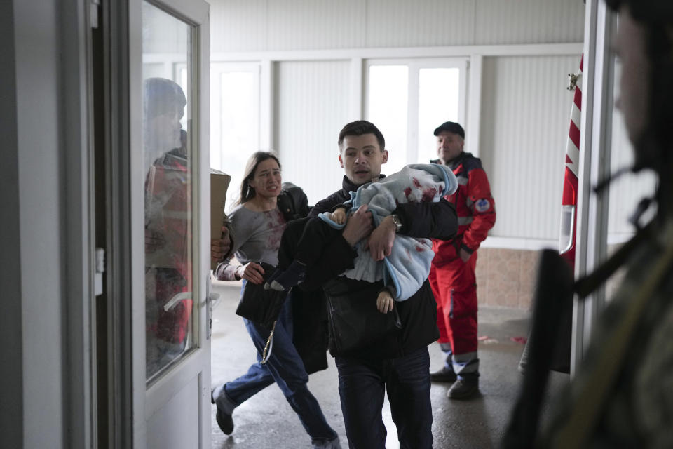 FILE - Marina Yatsko, left, runs behind her boyfriend Fedor carrying her 18 month-old son Kirill who was killed in shelling, as they arrive at a hospital in Mariupol, Ukraine, Friday, March 4, 2022. (AP Photo/Evgeniy Maloletka, File)