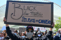 Eine Demonstrantin mit Stoffmaske hält ein Schild mit der Aufschrift "Black Lives Matter. Silence = Complice" während eines Protests gegen Rassismus und Polizeigewalt. Foto: Bernard Gillet / BELGA / dpa