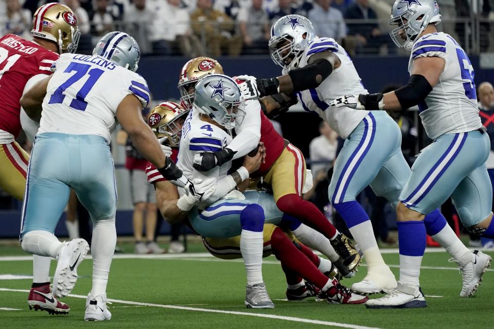 FILE -Dallas Cowboys quarterback Dak Prescott (4) is sacked by San Francisco 49ers defensive end Nick Bosa, center left rear, with help in the first half of an NFL wild-card playoff football game in Arlington, Texas, Sunday, Jan. 16, 2022. The 49ers-Cowboys playoff history is a rich one from back-to-back conference title games in the early 1970s, the iconic “Catch” in the 1981 season and then the heated rivalry in the 1990s when the Cowboys won the first two meetings on the way to Super Bowl titles and then the Niners took the third game. (AP Photo/Tony Gutierrez)