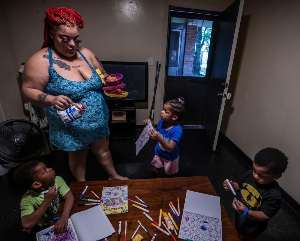 Lexus Ikeard, back left, brings dinner to her children Travis Lawless, left, Armoniie Lawless, center, and Noah Lawless, right, at their residence in Nashville on Wednesday, August 25, 2021.