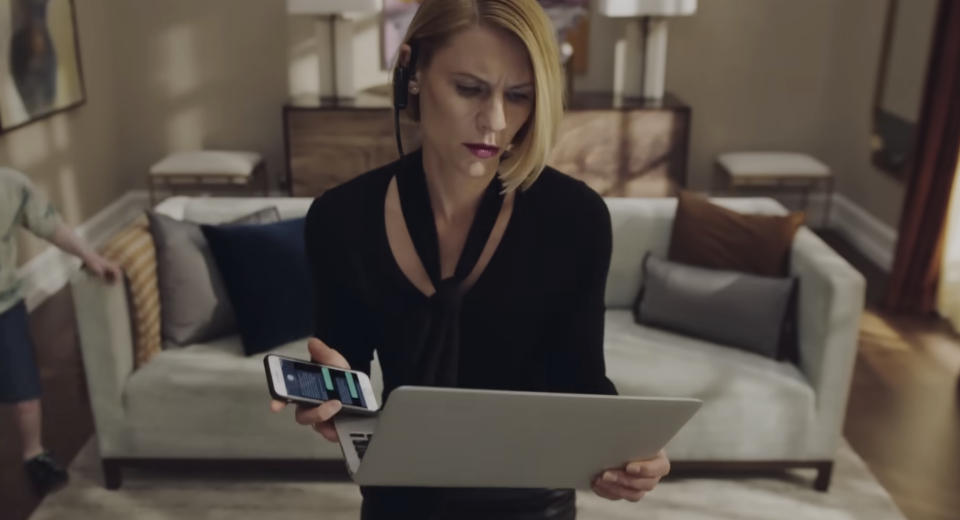 woman holding her phone and laptop open in her hands