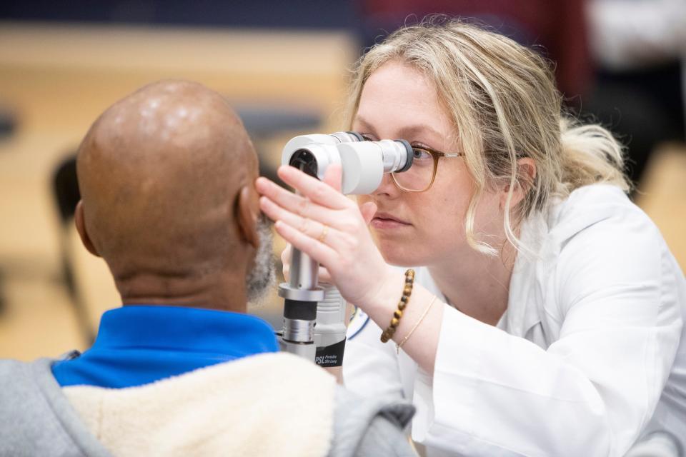 Kendall Cooper, a second-year student at Southern College of Optometry, checks the health of the front surface of an unhoused man’s eyes during the Project Homeless Connect event at the Memphis Sports and Events Center in Memphis, Tenn., on Thursday, January 25, 2024. The students were giving any of the unhoused attendees a comprehensive eye exam and they could leave with a free pair of glasses.