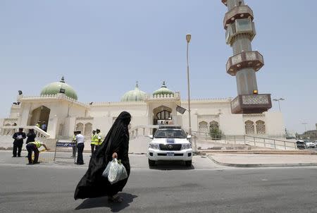 A woman walks in front of the Al A'ali Grand Mosque as police set up security check points and block an area, where joint Sunni and Shi'ites prayers are to be held to show solidarity and co-existence between the two sects of Islam, ahead of Friday prayers in Al A'ali south of Manama, July 3, 2015. REUTERS/Hamad I Mohammed