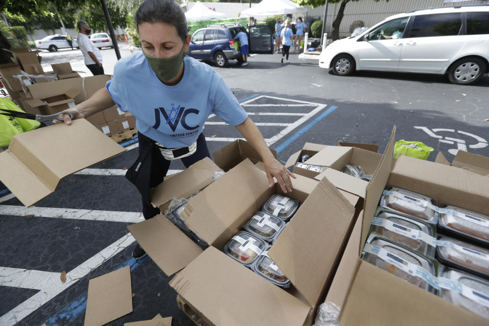 Volunteer Malka Rodrig unpacks meals at a kosher food drive-thru distribution site, Wednesday, July 29, 2020, at the Greater Miami Jewish Federation building in Miami. (AP Photo/Wilfredo Lee)