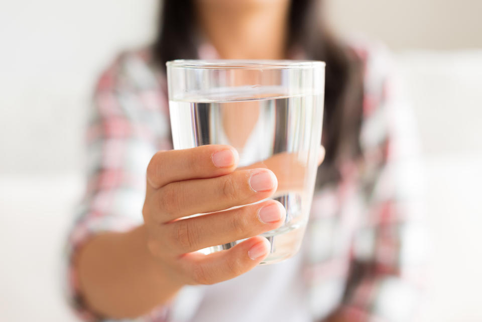 Happy beautiful young woman holding drinking water glass in her hand. Health care concept.