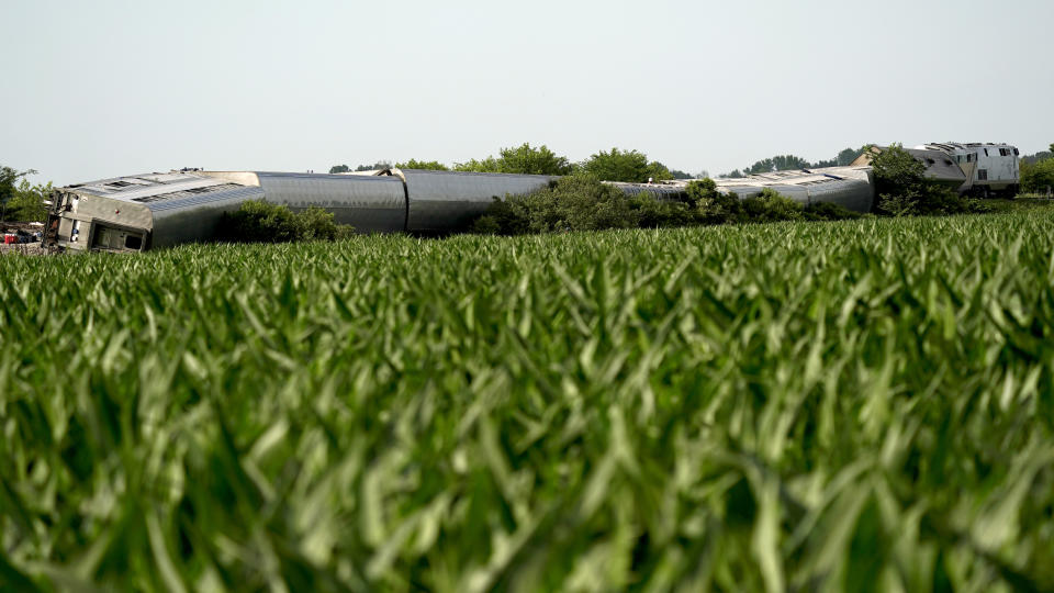 An Amtrak train which derailed after striking a dump truck is seen beyond a corn field Monday, June 27, 2022, near Mendon, Mo. (AP Photo/Charlie Riedel)