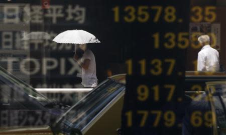 People are reflected on a stock quotation board displaying Japan's Nikkei average (top) and other markets' indices outside a brokerage in Tokyo August 16, 2013. REUTERS/Toru Hanai