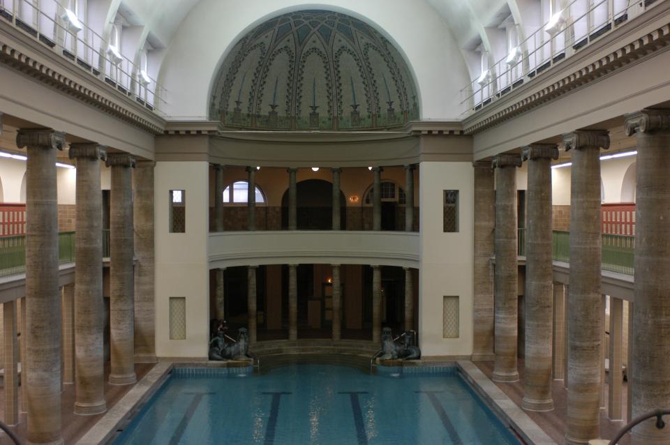 Berlin’s <strong>Neukoelln</strong> indoor pool allows users to take a dip in a different era of German architecture. Architect Reinhold Kiehl crafted Neukoelln in 1914, complementing it with vaulted roofs, many mosaics, and colonnades.