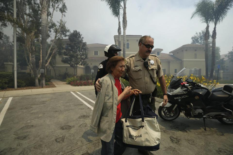 A woman is evacuated from her building during a wildfire Wednesday, May 14, 2014, in Carlsbad, Calif. More wildfires broke out Wednesday in San Diego County — threatening homes in Carlsbad and forcing the evacuations of military housing and an elementary school at Camp Pendleton — as Southern California is in the grip of a heat wave. (AP Photo)