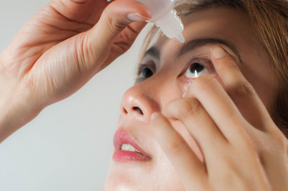 Person administering eye drops, tilting head back and looking up