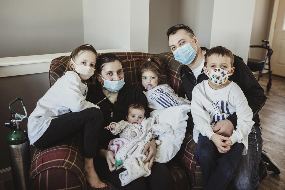 In this Jan. 27, 2021 photo provided by Taryn Marie Photography, the Townsend family poses for a photo in Poynette, Wis. the day mother Kelsey Townsend came home from the hospital, nearly three months after being admitted due to COVID-19. Townsend, second from left, gave birth to Lucy, in her arms, via C-section on Nov. 4 while in a medically induced coma. She spent 75 days on lung and life support. She finally met the daughter she delivered face to face on Jan. 27. (Taryn Ziegler/Taryn Marie Photography via AP)