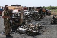 <p>A Pakistan army soldier stands guards while rescue workers examine the site of an oil tanker explosion at a highway near Bahawalpur, Pakistan, Sunday, June 25, 2017. An overturned oil tanker burst into flames in Pakistan on Sunday, killing over one hundred people who had rushed to the scene of the highway accident to gather leaking fuel, an official said. (AP Photo/Iram Asim) </p>