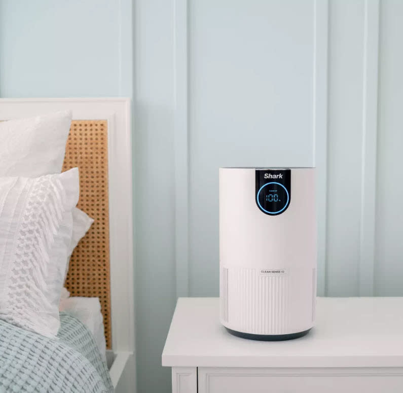 An air purifier on a bedside table in a bedroom