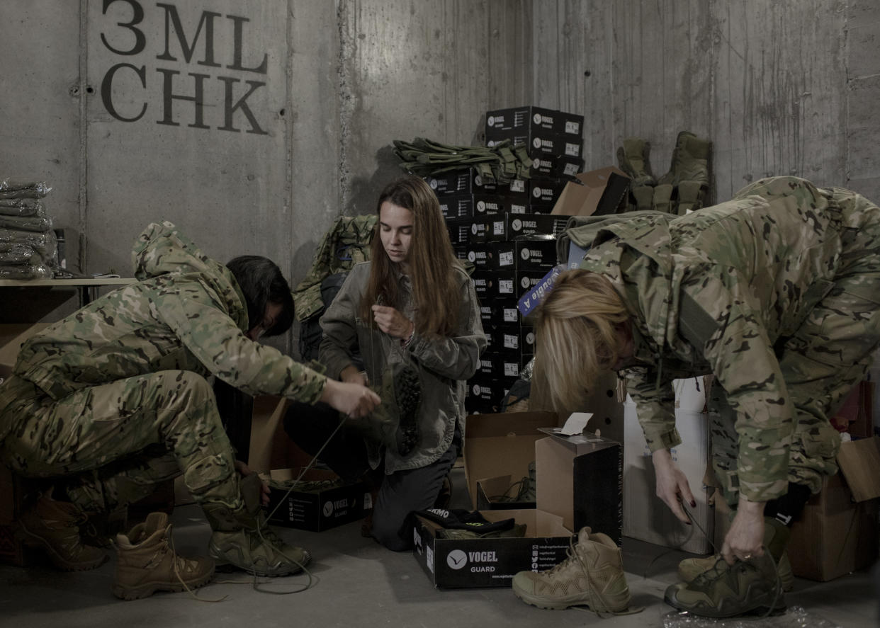 Kseniia Drahaniuk, en el centro, cuya organización sin fines de lucro 'Zemliatchki' aboga por las mujeres soldado ucranianas, entrega uniformes donados a Mariia Stalinska, a la izquierda, y Liliia Fedorenko, a la derecha, en Kiev, Ucrania, el 2 de noviembre de 2022. (Emile Ducke/The New York Times)