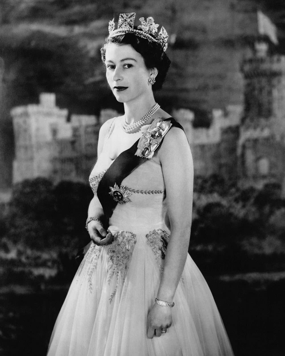 Queen Elizabeth wearing a royal sash and gown in a regal pose.