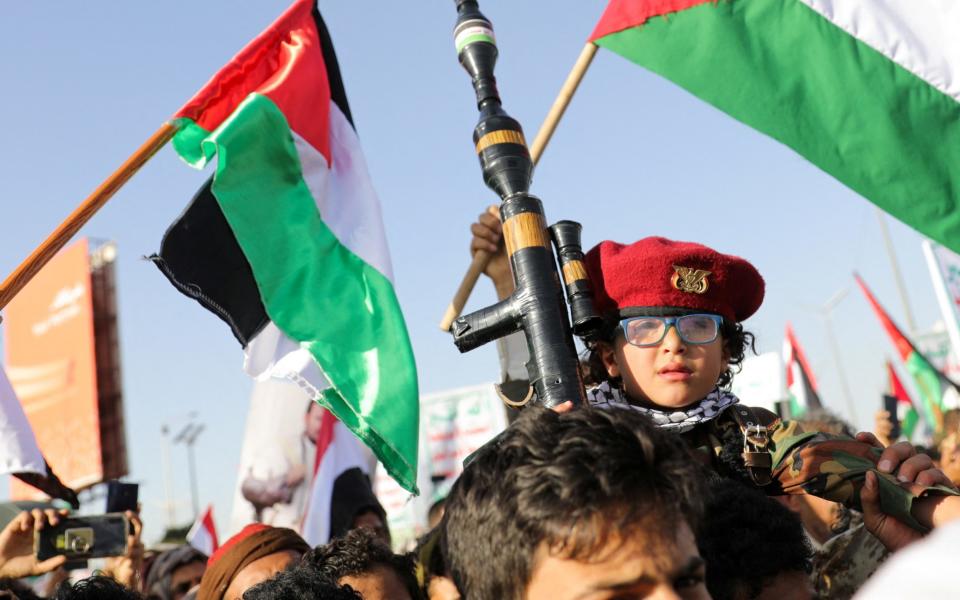 A child holds up a mock RPG, as supporters of the Houthi movement rally to denounce air strikes, in Sana'a, Yemen