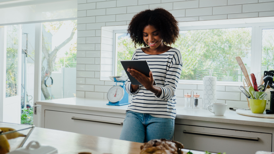 Woman browsing on a tablet in a home kitchen. - Cameron Prins/iStockphoto
