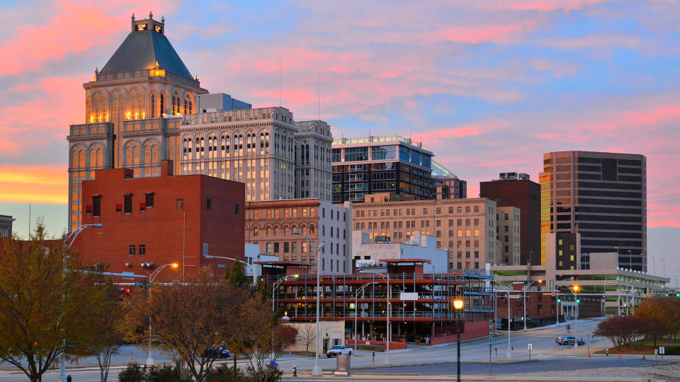 Greensboro skyline with pink, orange, and yellow at sunset.