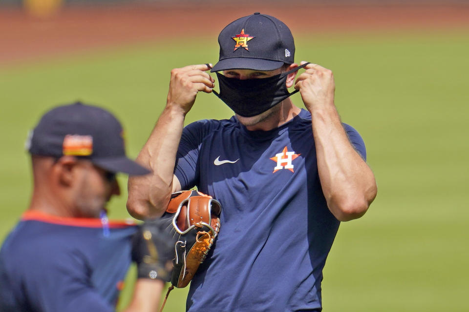 Houston Astros third baseman Alex Bregman, right, puts on a mask during a baseball practice Friday, July 3, 2020, at Minute Maid Park, in Houston. The Astros started workouts at the ballpark Friday as they and other Major League Baseball teams return amid the COVID-19 pandemic. (AP Photo/David J. Phillip)