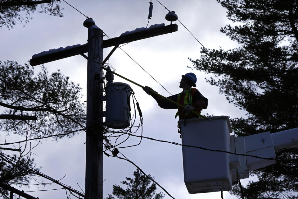 FILE - Lineman Tyler Hunter, of Newmarket, Ontario, Canada, clears pine tree limbs from electric lines in a neighborhood of about 70 houses without power, March 15, 2023, in Windham, N.H. The state of New Hampshire has highlighted a new entrant into the northeast transmission mix by announcing plans for a 211-mile, 1,200 megawatt power line that would enter the United States at Canaan, Vermont, and follow a buried route south along a state highway until it crossed into New Hampshire where it would hook up to an existing power right-of-way. (AP Photo/Charles Krupa, File)