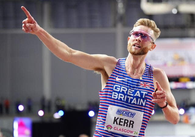 Josh Kerr, wearing glasses, points upwards after a race