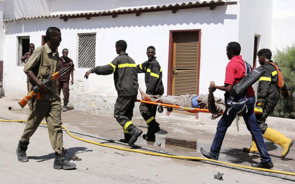 Rescuers carry a survivor from the scene of a blast at the Central Hotel after a suicide attack in Mogadishu