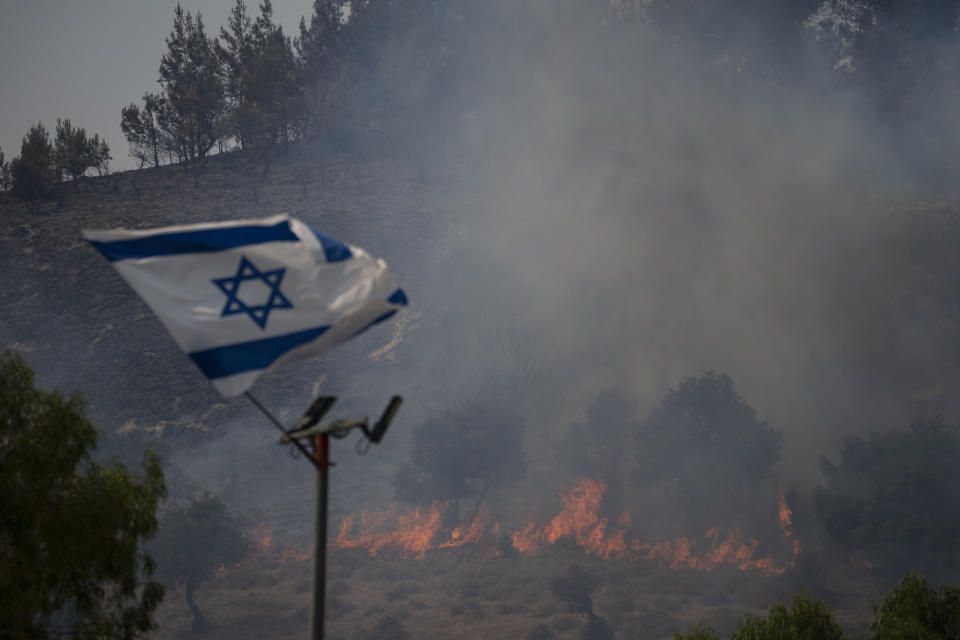 Una bandera israelí ondea en una zona que es arrasada por un incendio cerca de la frontera con el Líbano, en el norte de Israel en Safed, el miércoles 12 de junio de 2024. (AP Photo/Leo Correa, archivo)