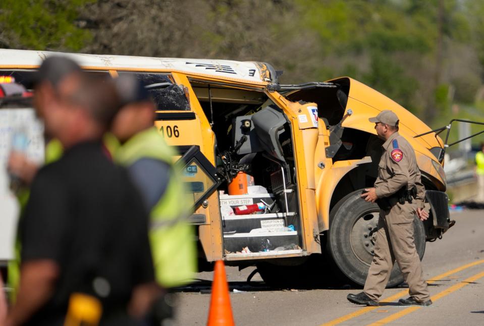 A DPS trooper looks at the wrecked school bus on Texas 71 near Caldwell Road.