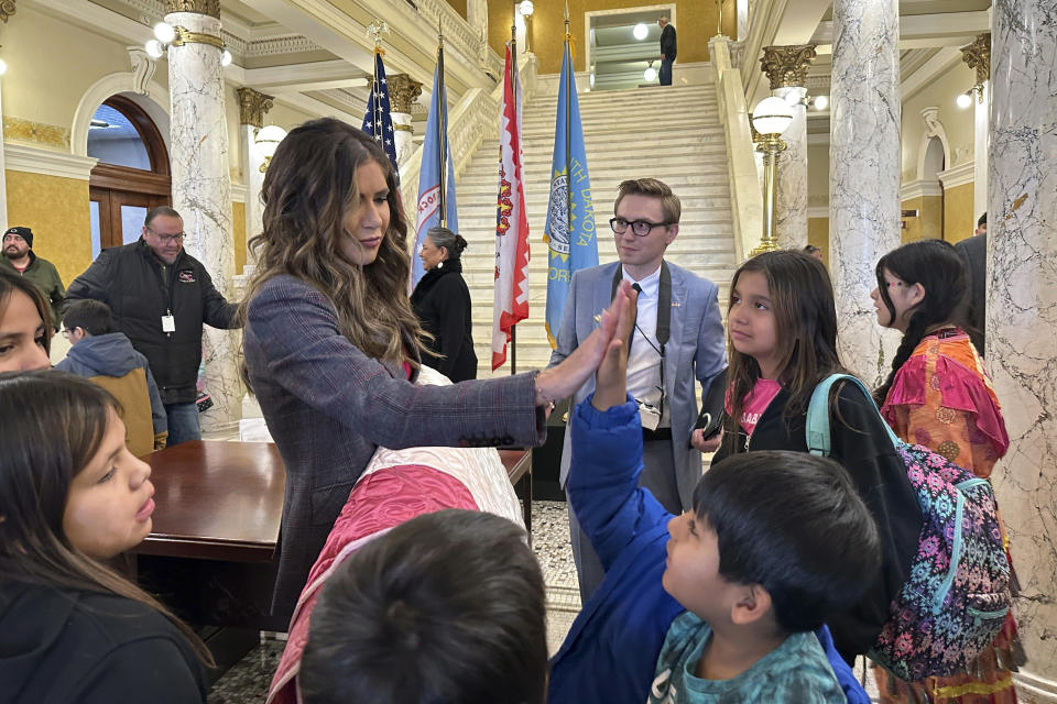 South Dakota Republican Gov. Kristi Noem greets children after a ceremony for the flags of the Standing Rock and Rosebud Sioux tribes in the rotunda of the state Capitol in Pierre, S.D., Wednesday, Jan. 10, 2024. Representatives from the two tribes presented the flags to Noem, whose office is in talks with the seven other tribes within South Dakota's boundaries about inviting them to offer a flag for display. Standing Rock and Rosebud tribal leaders praised the display of their flags as cooperative and unifying. (AP Photo/Jack Dura)