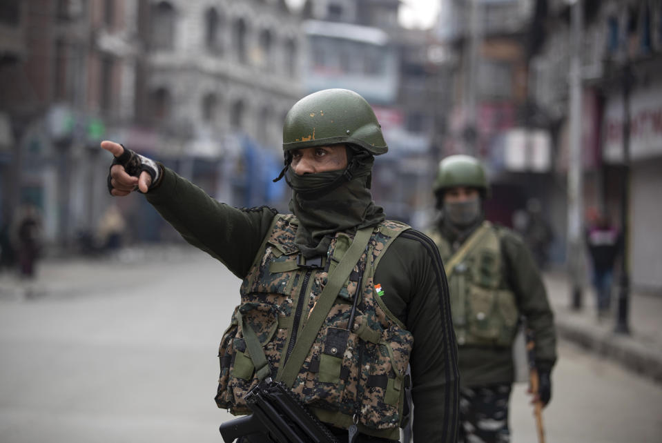 An Indian paramilitary officer points towards civilians as they patrol a closed market in Srinagar, Indian controlled Kashmir, Tuesday, Feb. 9, 2021. Businesses and shops have closed in many parts of Indian-controlled Kashmir to mark the eighth anniversary of the secret execution of a Kashmiri man in New Delhi. Hundreds of armed police and paramilitary soldiers in riot gear patrolled as most residents stayed indoors in the disputed region’s main city of Srinagar. (AP Photo/Mukhtar Khan)