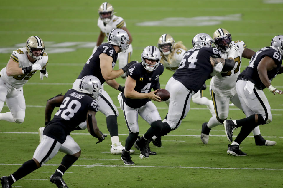 Las Vegas Raiders quarterback Derek Carr (4) prepares to hand the ball off to running back Josh Jacobs (28) during the first half of an NFL football game, Monday, Sept. 21, 2020, in Las Vegas. (AP Photo/Isaac Brekken)