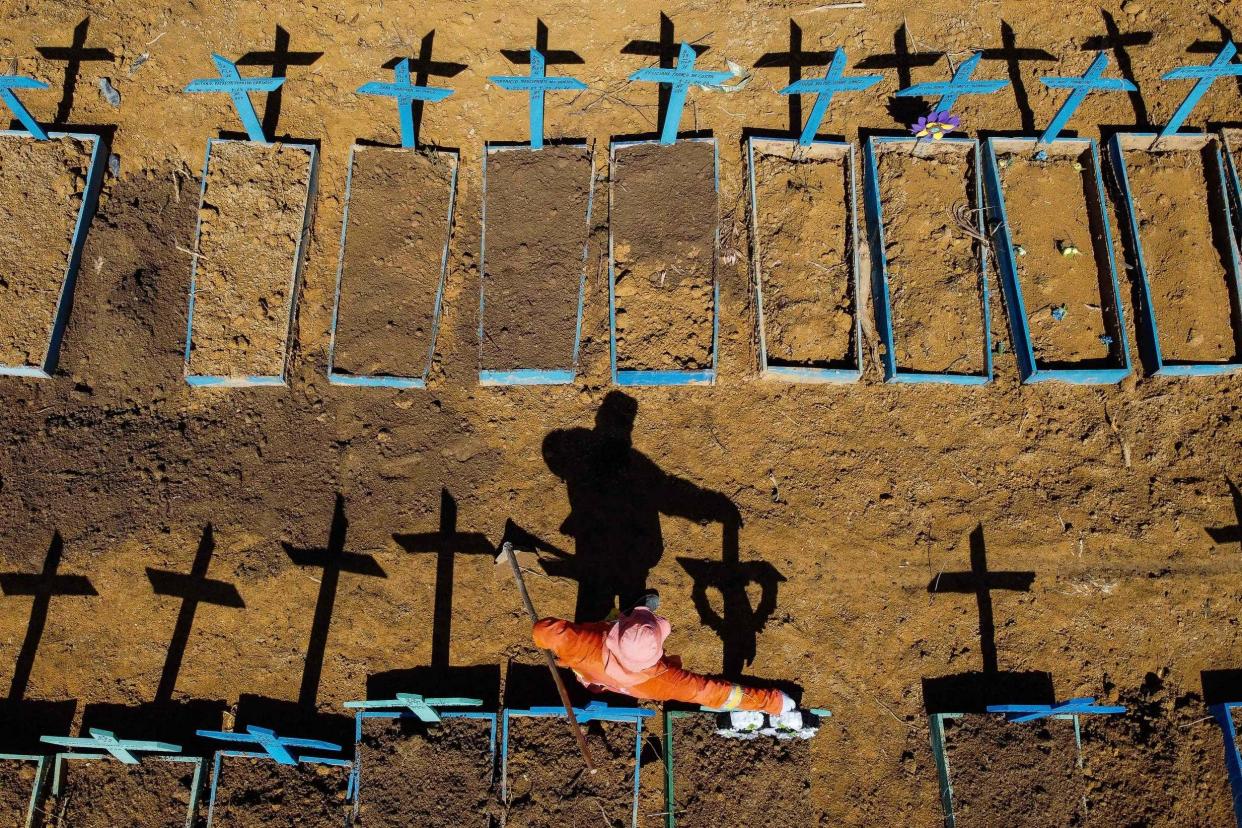 This file aerial photo taken on June 2, 2020 shows a gravedigger standing at the Nossa Senhora Aparecida cemetery where COVID-19 victims are buried daily, in the neighbourhood of Taruma, in Manaus, Brazil: AFP via Getty Images