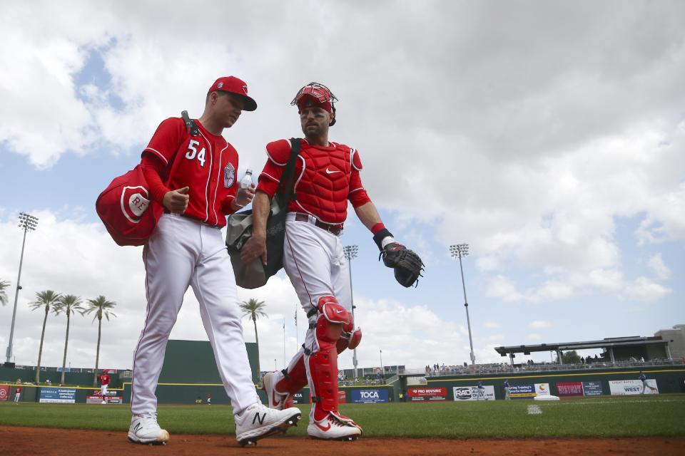 Cincinnati Reds starting pitcher Sonny Gray (54) talks with catcher Curt Casali as they walk to the dugout after warming up in the bullpen prior to a spring training baseball game against the Los Angeles Dodgers, Monday, March 2, 2020, in Goodyear, Ariz. (AP Photo/Ross D. Franklin)