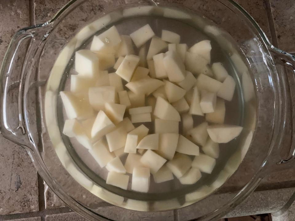 Chopped potato pieces soaking in a glass bowl of water