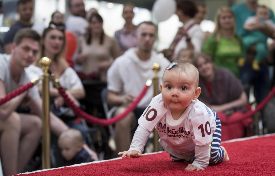 A baby crawls during the Baby Race event to mark international Children's Day in Vilnius, Lithuania, Saturday, June 1, 2019. Twenty five babies took part in the crawl competition with red carpet to protect their knees, as mums, dads, grandparents and other onlookers encourage the competitors.(AP Photo/Mindaugas Kulbis)
