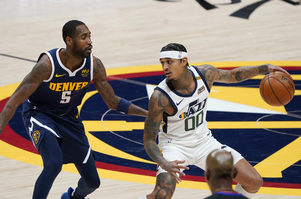 Utah Jazz guard Jordan Clarkson, right, looks to pass the ball as Denver Nuggets forward Will Barton defends in the first half of an NBA basketball game Sunday, Jan. 17, 2021, in Denver. (AP Photo/David Zalubowski)