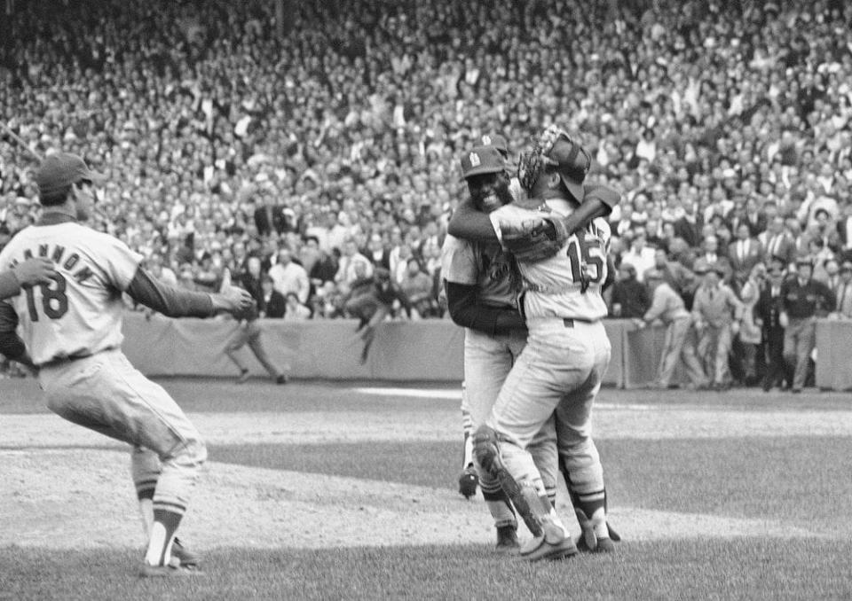 In this Oct. 12, 1967, file photo, St. Louis Cardinals pitcher Bob Gibson receives a congratulatory hug from catcher Tim McCarver after he pitched a three-hitter in the team’s 7-2 victory in Game 7 over the Boston Red Sox to win the World Series at Fenway Park in Boston, Mass. At left is third baseman Mike Shannon. (AP Photo, File)