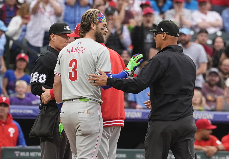 Philadelphia Phillies' Bryce Harper talks to umpire Vic Carapazza, right, after home plate umpire Brian Walsh ejected Harper for arguing a strikeout against Colorado Rockies starting pitcher Ty Blach to end the top of the first inning of a baseball game Friday, May 24, 2024, in Denver. (AP Photo/David Zalubowski)