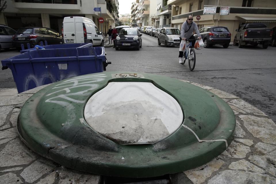 A cyclist passes near a garbage dumpster in Kalamata, southern Greece, Wednesday, Dec. 18, 2019. Greek police say they have arrested a 24-year-old foreign woman on suspicion of attempted infanticide after a passer-by found a days-old baby inside this in-ground garbage dumpster. (AP Photo/Nikolia Apostolou)