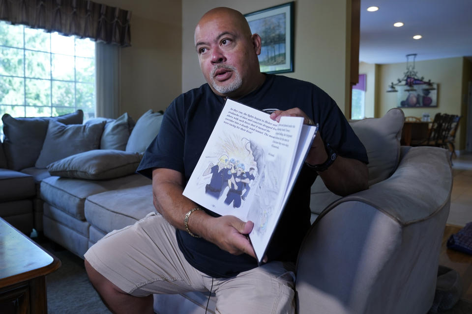 Will Jimeno, the former Port Authority police officer who was rescued from the rubble of the Sept. 11, 2001 attacks at the World Trader Center after many hours, holds the children's book he wrote, "Immigrant, American, Survivor," that draws on his experience, during an interview at his home in Chester, N.J., Monday, Aug. 2, 2021. (AP Photo/Richard Drew)
