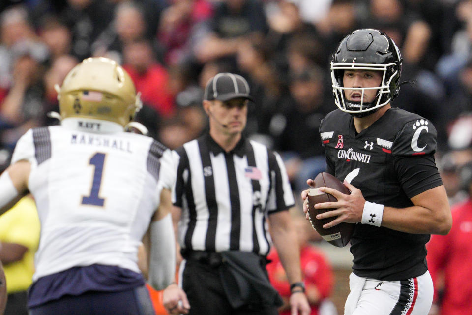 Cincinnati quarterback Ben Bryant, right, looks to pass the ball during the first half of an NCAA college football game against Navy, Saturday, Nov. 5, 2022, in Cincinnati. (AP Photo/Jeff Dean)