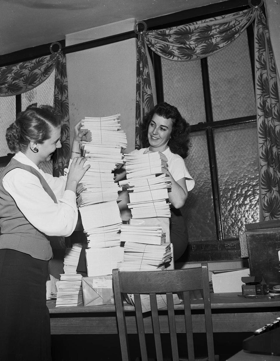 Sept 27, 1950: Mrs. Marilyn Basham; left, and Miss Robbie Barrett, Community Chest clerical workers, exhibit part of the 50,000 pledge cards they and other office workers had typed for the employee division gifts drive. The cards were distributed to team captains in preparation for the kickoff of the employee division drive.