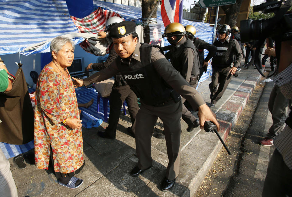 A riot policeman removes a woman from her tent as they retake a stretch of a road occupied by anti-government protesters in Bangkok, Thailand, Friday, Feb. 14, 2014. Riot police cleared the protesters from a major boulevard in the Thai capital in a small victory for authorities Friday as they try to reclaim areas that have been closed during a three-month push to unseat Prime Minister Yingluck Shinawatra. (AP Photo/Wally Santana)